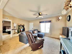 Carpeted living room featuring ceiling fan and visible vents