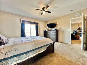 Carpeted bedroom featuring visible vents and ceiling fan