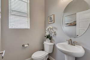 Half bathroom with baseboards, a sink, and toilet
