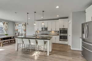 Kitchen featuring a sink, appliances with stainless steel finishes, dark countertops, a kitchen bar, and backsplash