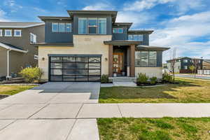 View of front facade with driveway, a garage, stone siding, and a front lawn