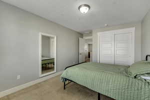 Bedroom with a textured ceiling, a closet, baseboards, and carpet floors