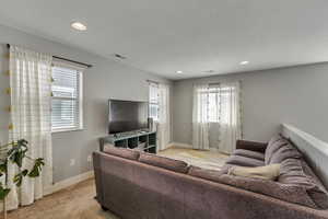 Living area with visible vents, baseboards, a textured ceiling, and a healthy amount of sunlight