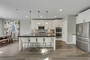 Kitchen with dark countertops, tasteful backsplash, a sink, and appliances with stainless steel finishes
