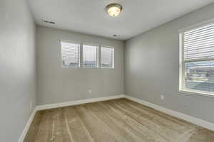 Empty room featuring visible vents, baseboards, and light colored carpet