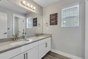Bathroom with visible vents, baseboards, a sink, and wood finished floors