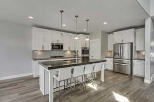 Kitchen featuring dark countertops, appliances with stainless steel finishes, wood finished floors, and a sink
