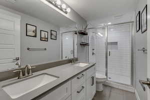 Bathroom with a sink, toilet, and a stall shower