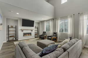 Living area with a glass covered fireplace, recessed lighting, light wood-type flooring, and baseboards