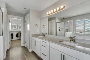 Full bath featuring a sink, visible vents, a shower stall, and wood finished floors