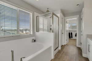 Full bathroom with a garden tub, vanity, visible vents, wood finished floors, and a stall shower
