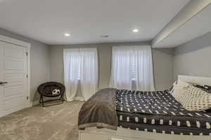 Carpeted bedroom with recessed lighting, visible vents, and multiple windows