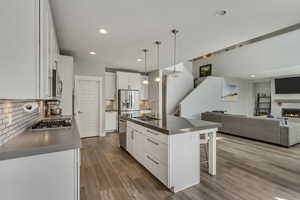 Kitchen featuring appliances with stainless steel finishes, a sink, dark countertops, open floor plan, and a breakfast bar area