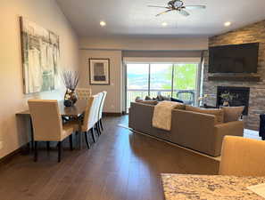 Living room with ceiling fan, a stone fireplace, dark wood-style flooring, and recessed lighting