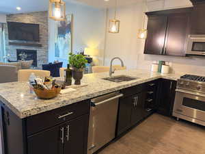 Kitchen with appliances with stainless steel finishes, open floor plan, tasteful backsplash, dark wood-type flooring, and light stone countertops
