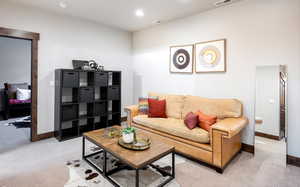 Living area with visible vents, baseboards, and light colored carpet