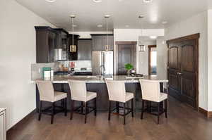 Kitchen featuring a kitchen bar, backsplash, a peninsula, appliances with stainless steel finishes, and light stone countertops