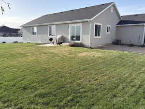 Back of house featuring a patio, central air condition unit, stucco siding, a yard, and fence