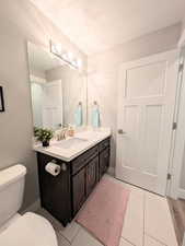 Bathroom with toilet, vanity, and a textured ceiling