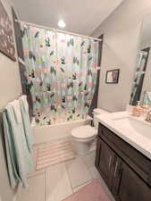 Full bathroom with shower / bathtub combination with curtain, vanity, a textured ceiling, and toilet