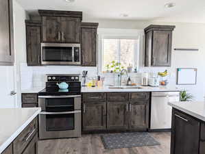 Kitchen with a sink, appliances with stainless steel finishes, and dark brown cabinetry