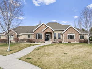 Ranch-style home featuring roof with shingles, a front yard, and brick siding