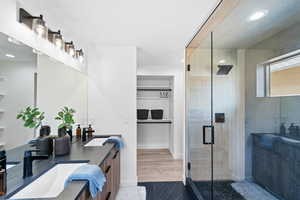 Bathroom with a shower stall, double vanity, a sink, and recessed lighting