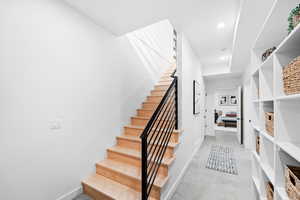 Staircase featuring concrete floors, baseboards, and recessed lighting