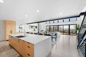 Kitchen with a kitchen island with sink, light brown cabinets, modern cabinets, and a sink