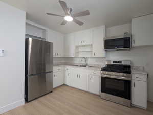 Kitchen featuring light countertops, a sink, open shelves, and appliances with stainless steel finishes
