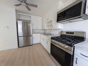 Kitchen featuring white cabinets, open shelves, a sink, light countertops, and stainless steel appliances