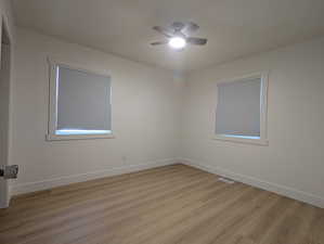 Empty room with visible vents, baseboards, a ceiling fan, and light wood-style floors