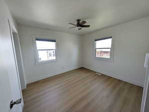Empty room with light wood-style flooring, ceiling fan, baseboards, and visible vents