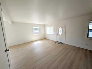Entrance foyer featuring light wood-style flooring, baseboards, and beam ceiling