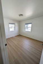 Spare room with a wealth of natural light, visible vents, light wood-type flooring, and baseboards