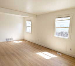 Spare room with light wood-type flooring, baseboards, and visible vents