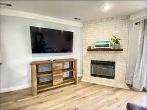 Living area with crown molding, visible vents, and wood finished floors