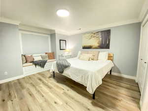 Bedroom with ornamental molding, baseboards, and wood finished floors