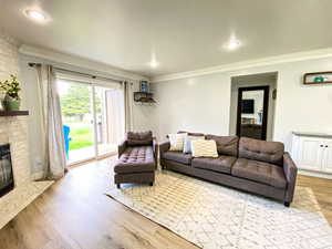 Living room with recessed lighting, a fireplace, ornamental molding, and wood finished floors