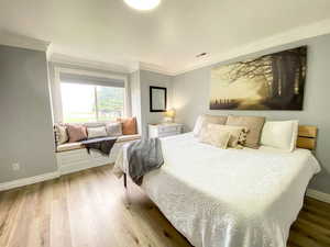 Bedroom with ornamental molding, visible vents, and light wood-type flooring