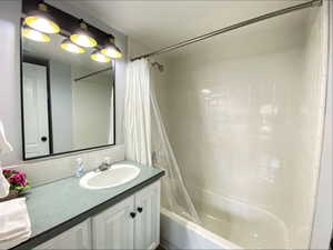 Bathroom with shower / bathtub combination with curtain and vanity
