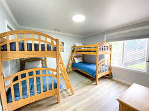 Bedroom with crown molding, wood finished floors, baseboards, and visible vents
