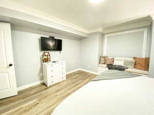 Bedroom with light wood-style flooring, crown molding, and baseboards