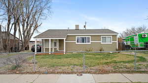 Bungalow-style home featuring a front lawn, a shingled roof, and a fenced front yard