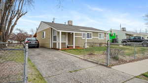 Bungalow-style house featuring roof with shingles, driveway, and a fenced front yard