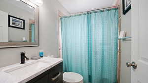 Full bath featuring toilet, a shower with shower curtain, and vanity