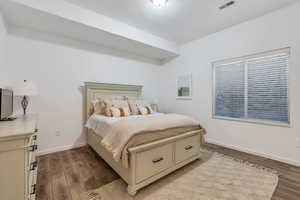 Bedroom with wood finished floors, baseboards, and visible vents