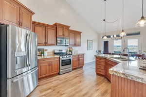 Kitchen with a sink, light wood-style flooring, appliances with stainless steel finishes, and brown cabinets