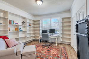 Office area with light wood-type flooring and ornamental molding