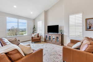 Living room with wood finished floors, high vaulted ceiling, baseboards, and recessed lighting